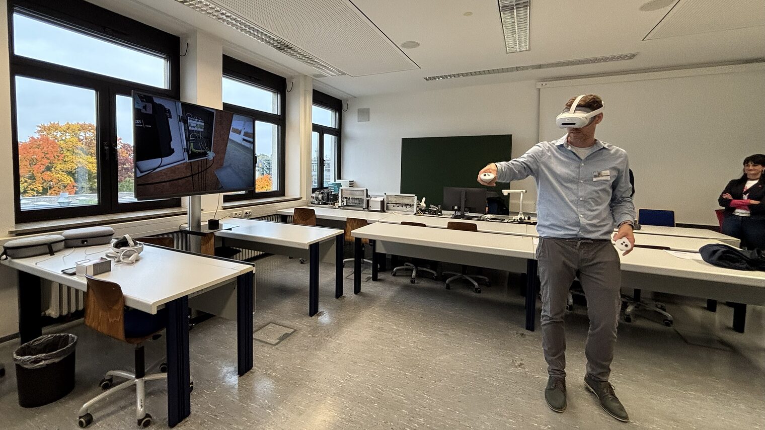 Stefan Kolb trägt eine VR-Brille und zeigt das Verkabeln eines Verteilerkastens am Bildschirm.