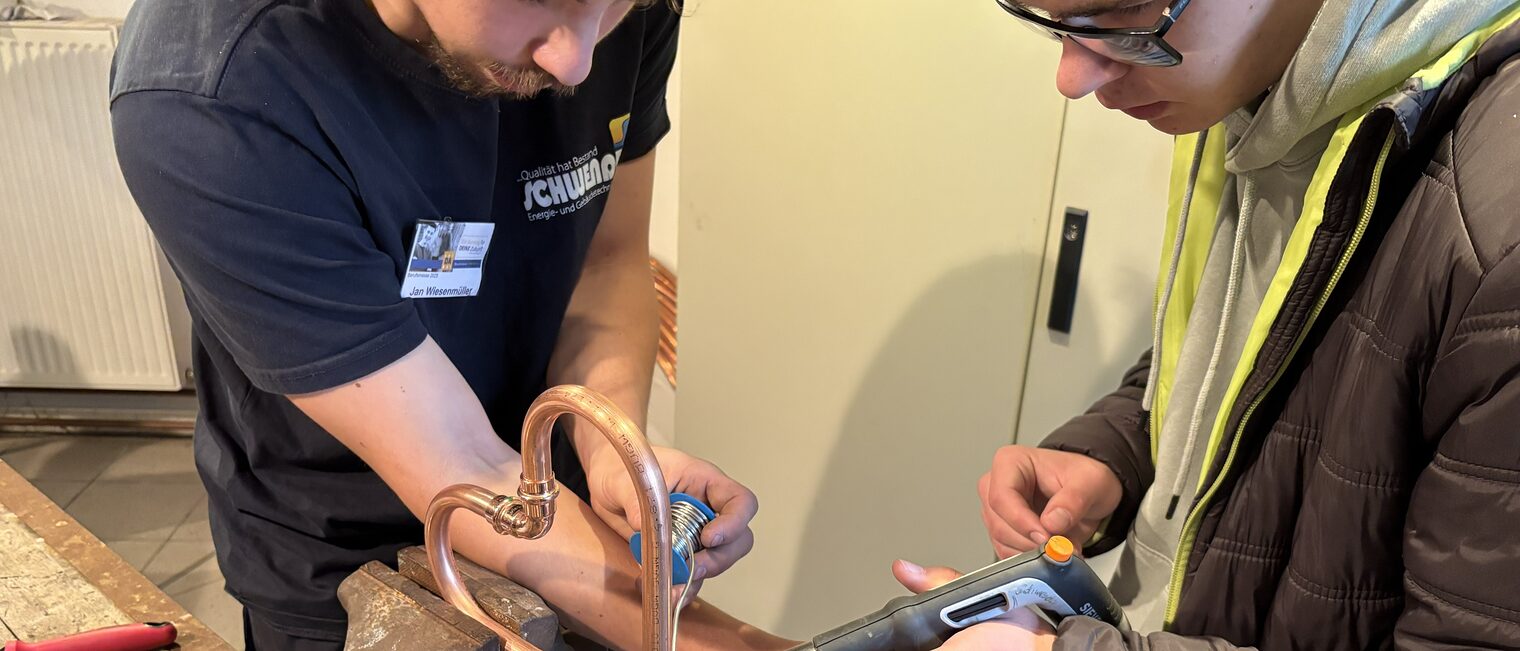 Stefan Kolb trägt eine VR-Brille und zeigt das Verkabeln eines Verteilerkastens am Bildschirm.