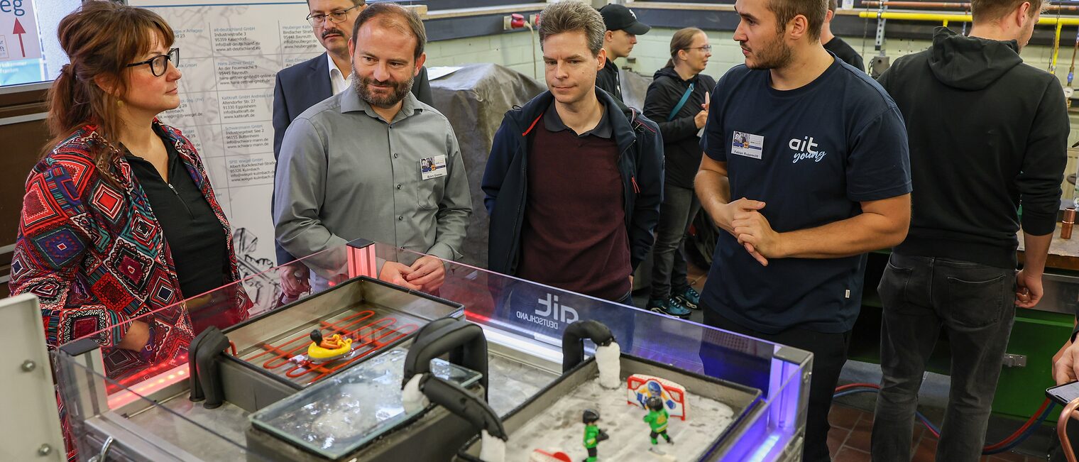 Die Ehrengäste betrachten ein Modell des Wärme- und Kälteleitsystems des Eisstadions und Stadtbades.