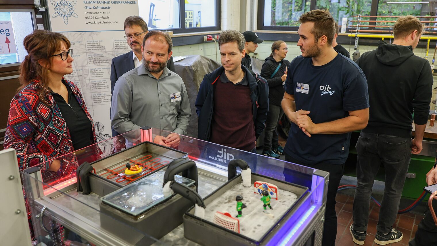 Die Ehrengäste betrachten ein Modell des Wärme- und Kälteleitsystems des Eisstadions und Stadtbades.