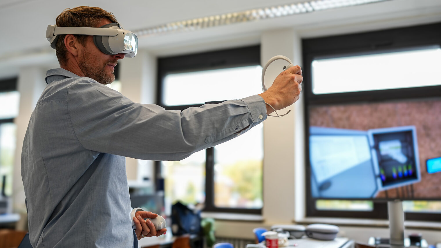 Ein junger Mann trägt eine VR-Brille und hält einen Controller in der Hand.