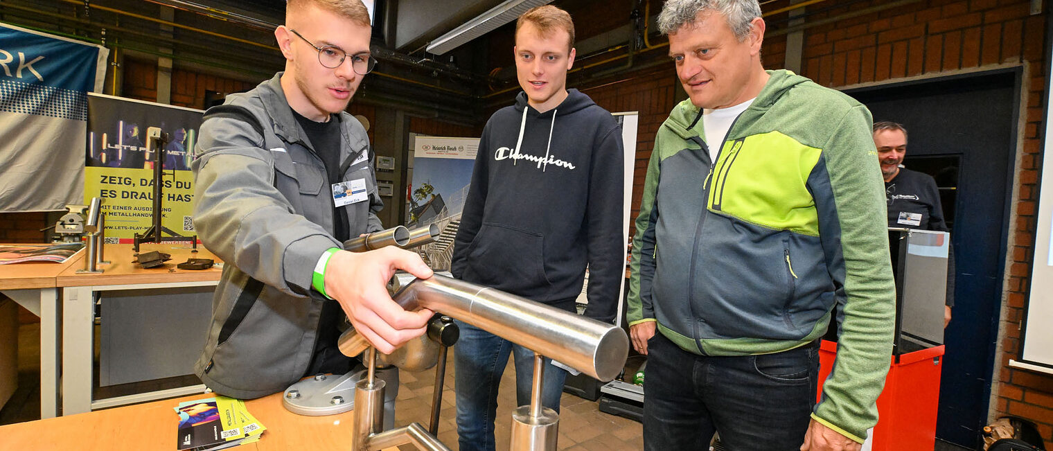 Ein Auszubildender setzt ein Geländer aus Metallrohren zusammen.