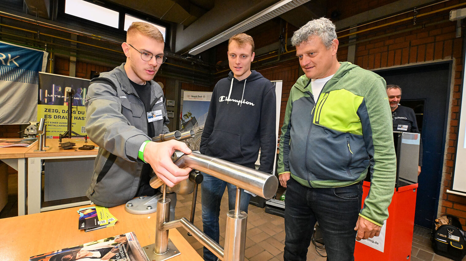 Ein Auszubildender setzt ein Geländer aus Metallrohren zusammen.