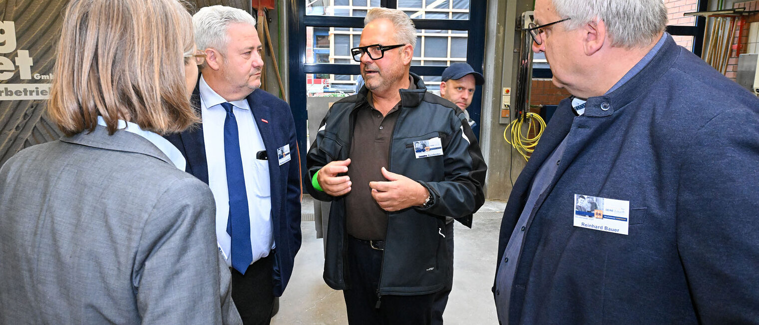 Matthias Graßmann, und Reinhard Bauer und Maria Emig unterhalten sich mit einem Handwerksmeister.