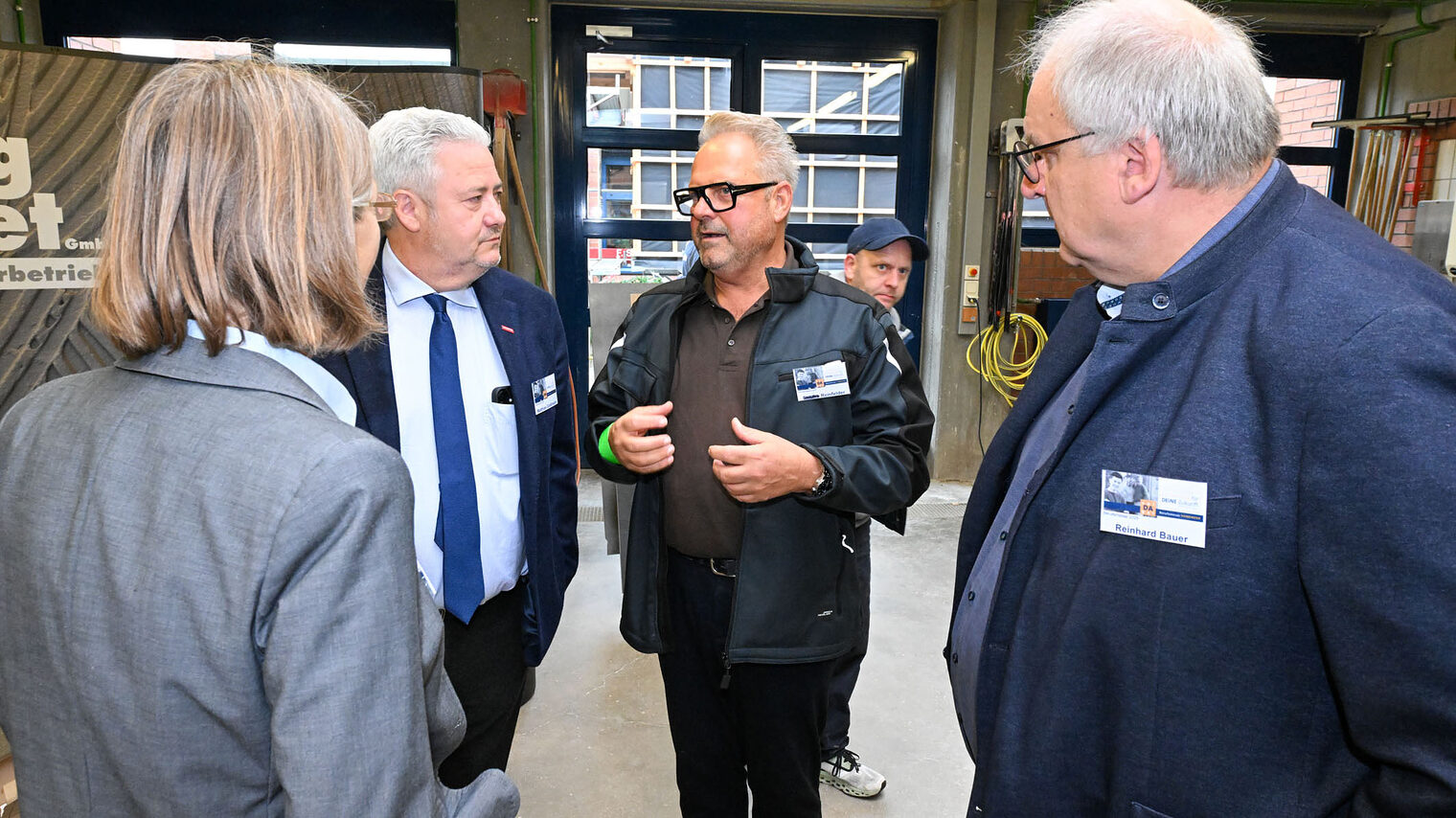 Matthias Graßmann, und Reinhard Bauer und Maria Emig unterhalten sich mit einem Handwerksmeister.