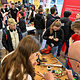 Jugendliche stehen um einen Stand herum und fertigen Metallherzen aus Kupfer.