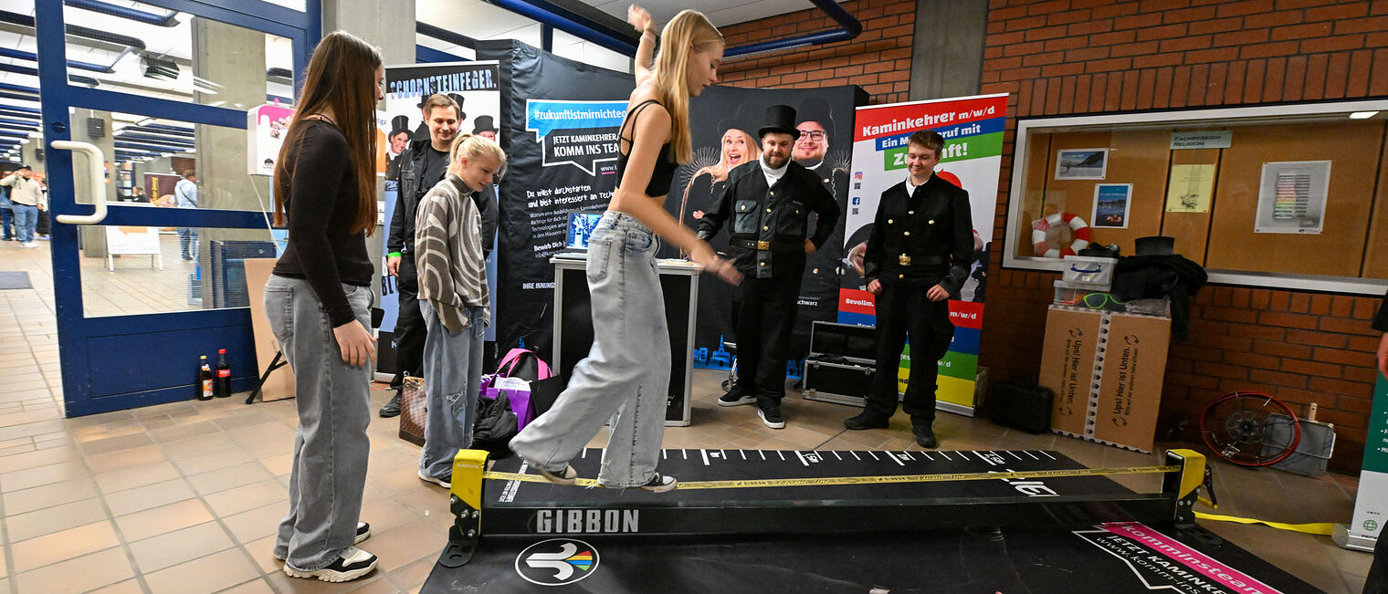 Eine Jugendliche balanciert unter Beaufsichtigung auf einer Slackline.