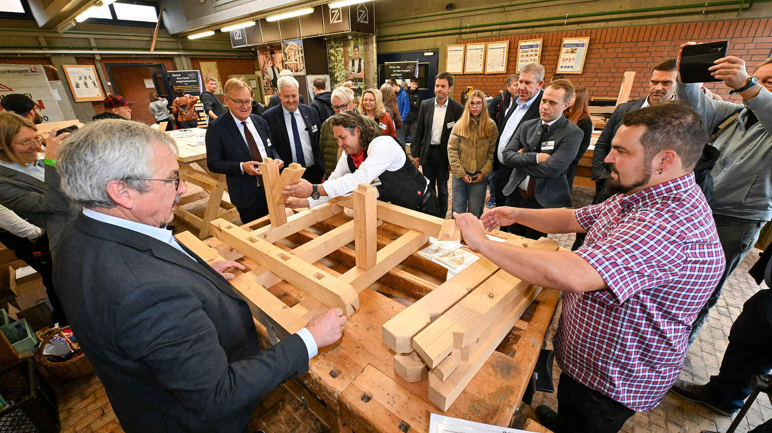 Die Ehrengäste sehen zu, wie eine Holzkonstruktion zusammengebaut wird.