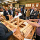 Die Ehrengäste sehen zu, wie eine Holzkonstruktion zusammengebaut wird.