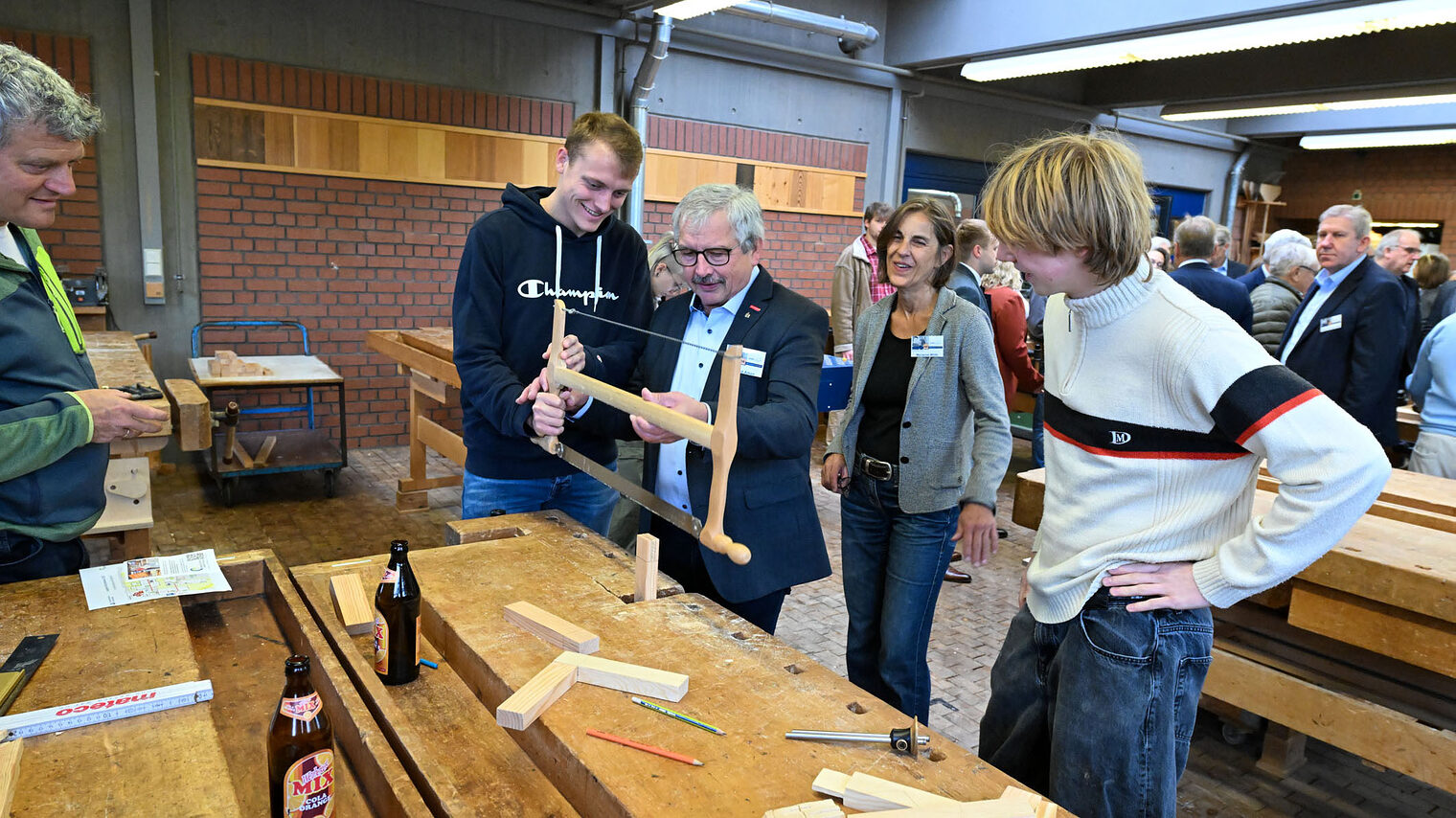 Wolfgang Ammon bedient eine Holzsäge während andere Menschen zusehen.