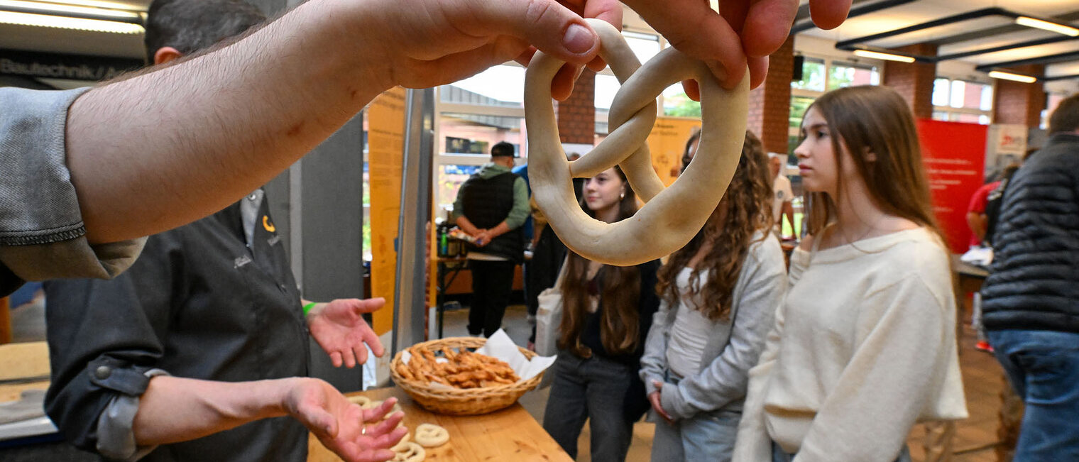 Jugendliche formen mit den Händen Teig zu Bretzeln.