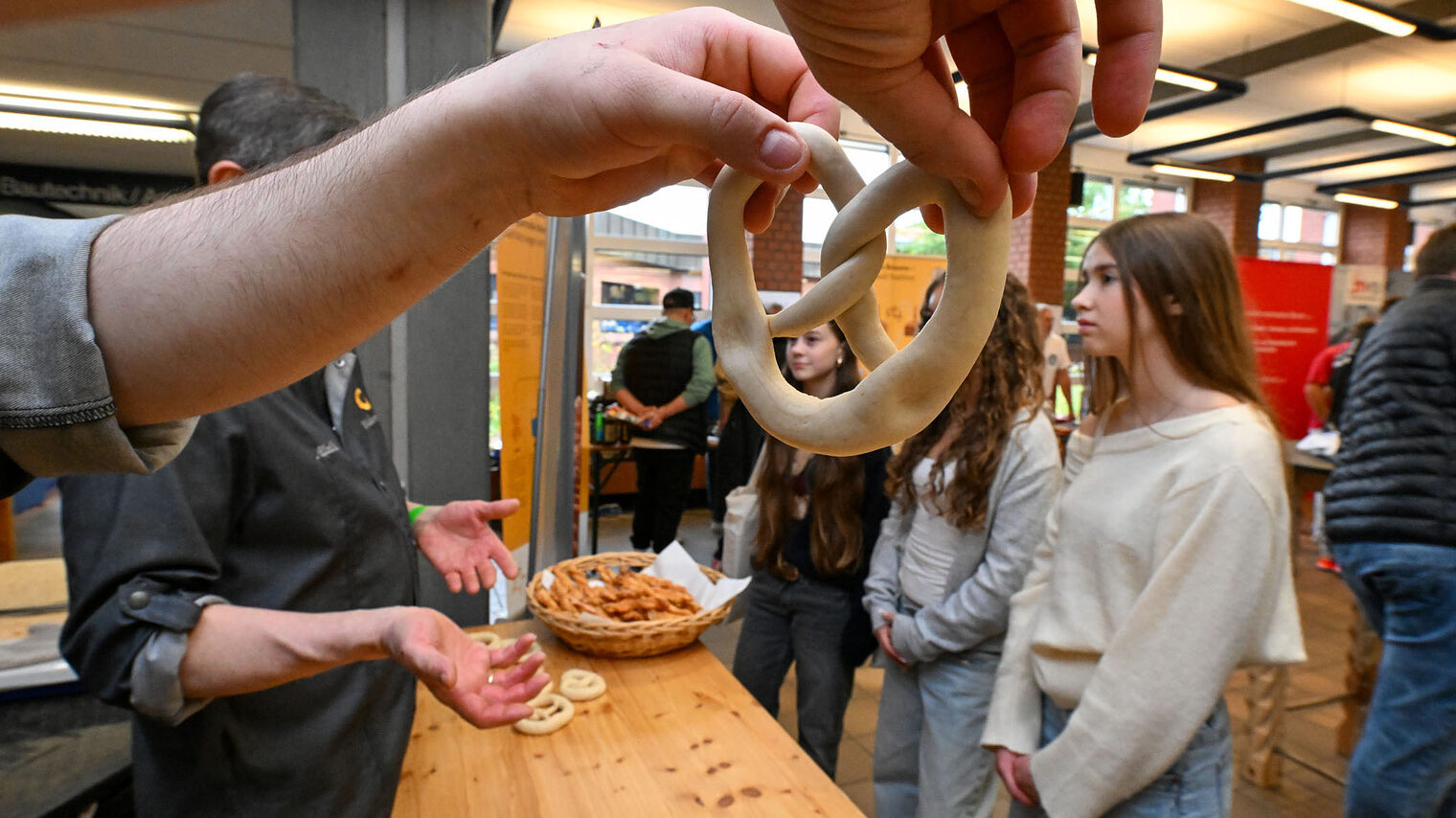 Jugendliche formen mit den Händen Teig zu Bretzeln.