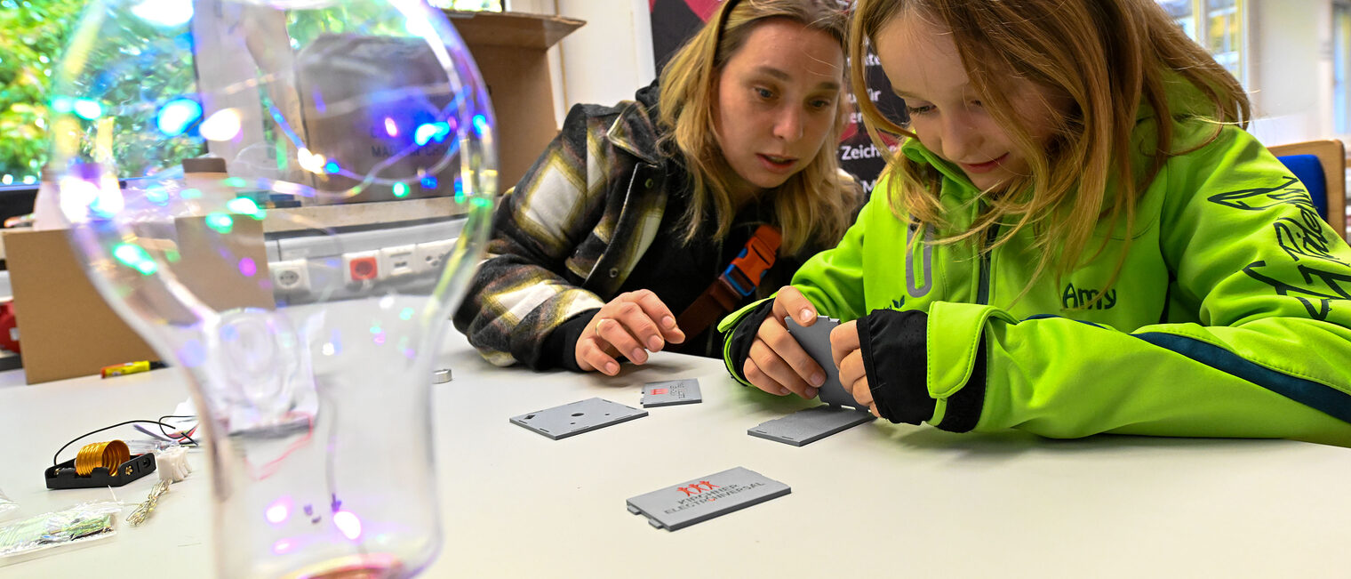 Eine Jugendliche bastelt einen Akku für eine Lampe zusammen.