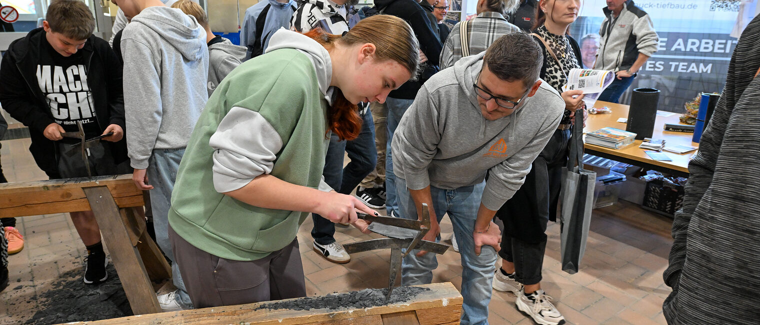 Eine Jugendliche hackt ein Herz aus Schiefer zurecht.