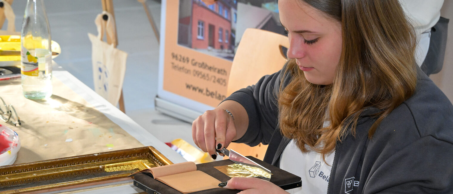 Eine Jugendliche streicht eine Goldfolie auf Polster zurecht. 