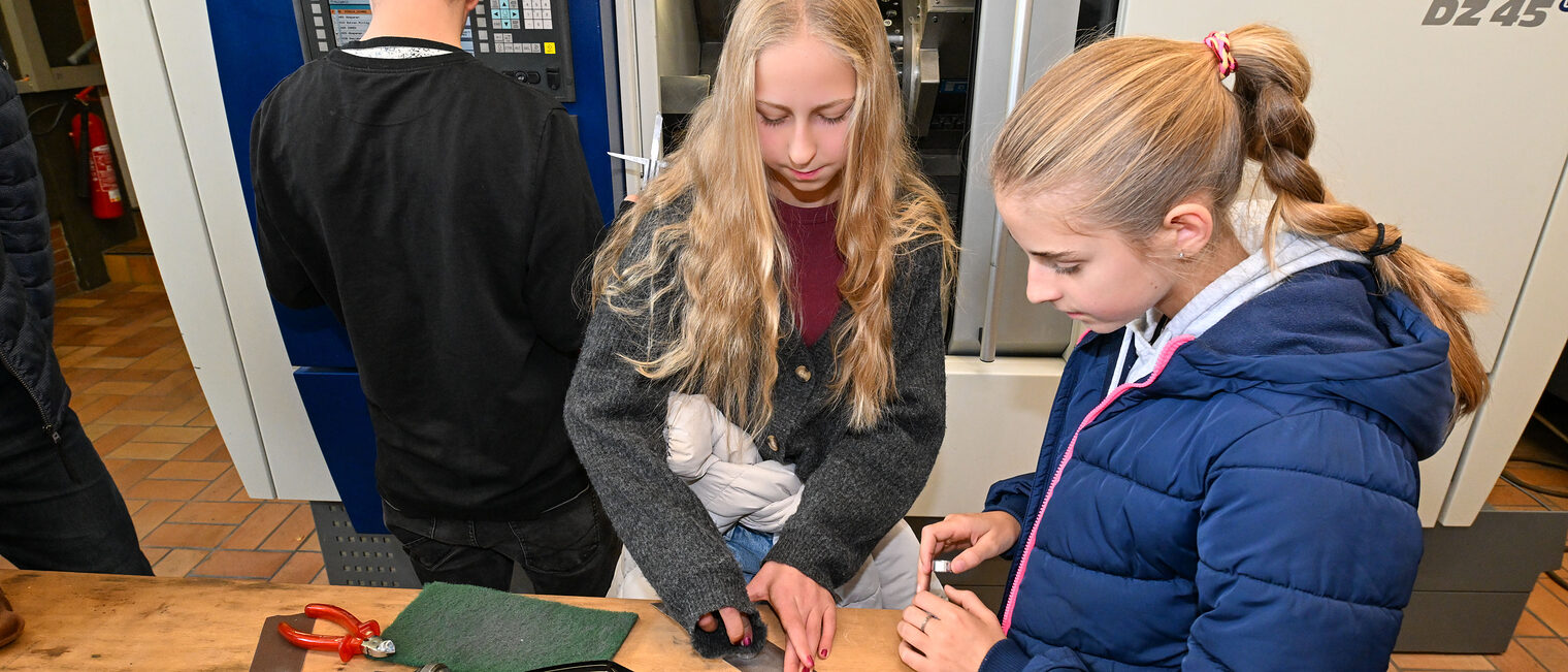 Zwei Jugendliche schleifen Schrauben mit Schleifpapier ab. 