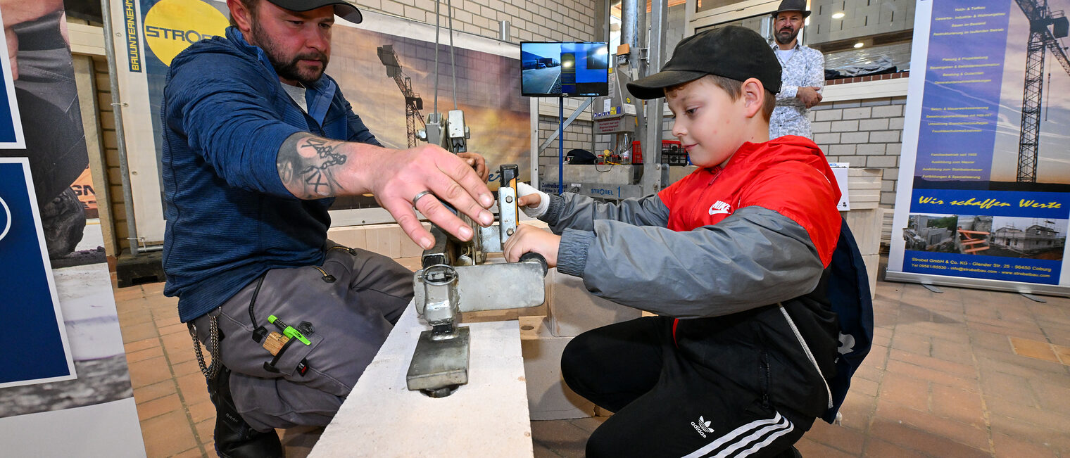 Ein Jugendlicher setzt ein Zugsystem auf einen Stein, um diesen anheben zu können.