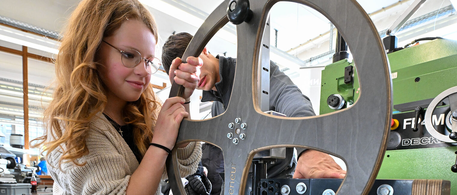Eine Jugendliche bedient eine Hebevorrichtung mit einem Steuerrad.