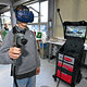 Ein Jugendlicher trägt eine VR-Brille und eine Spritzpistole und lackiert virtuell eine Autotür. 