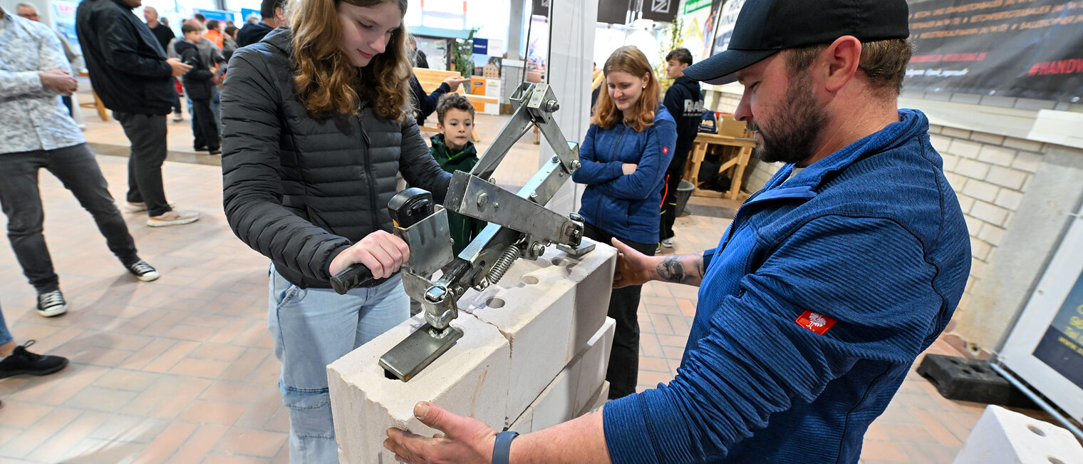 Eine Jugendliche benutzt ein mechanisches Zugsystem, um Steine anzuheben.