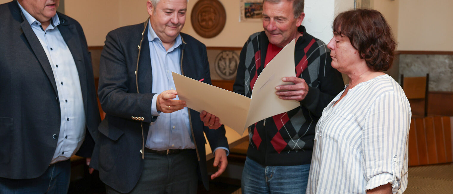 Michael Rindfleisch betrachtet seine Ehrenurkunde zusammen mit seiner Frau, Matthias Graßmann und Reinhard Bauer.