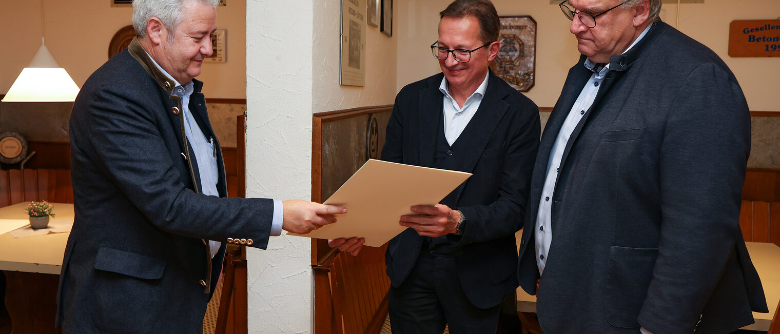 Matthias Graßmann übergibt Peter Hofmann seine Ehrenurkunde während Reinhard Bauer zusieht.