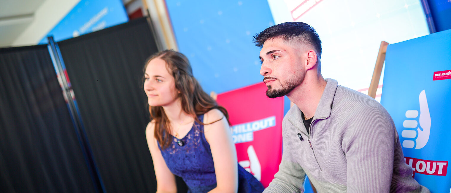 Zwei Landesiegerinnen und Landessieger verfolgen das Programm.