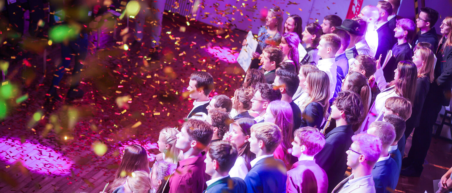 Die Landessiegerinnen und Landessieger stehen im Goldregen auf der Bühne.