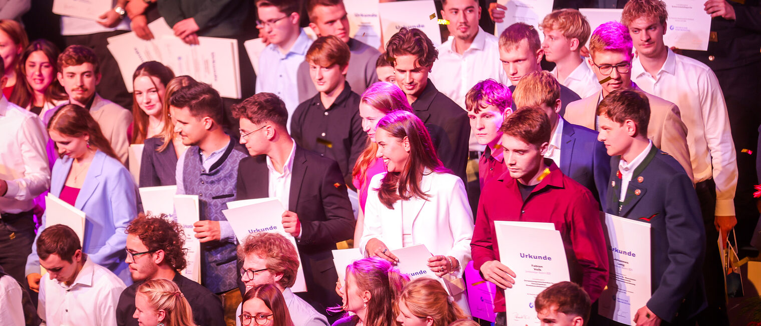 Die Landessiegerinnen und Landessieger präsentieren ihre Urkunden auf der Bühne.