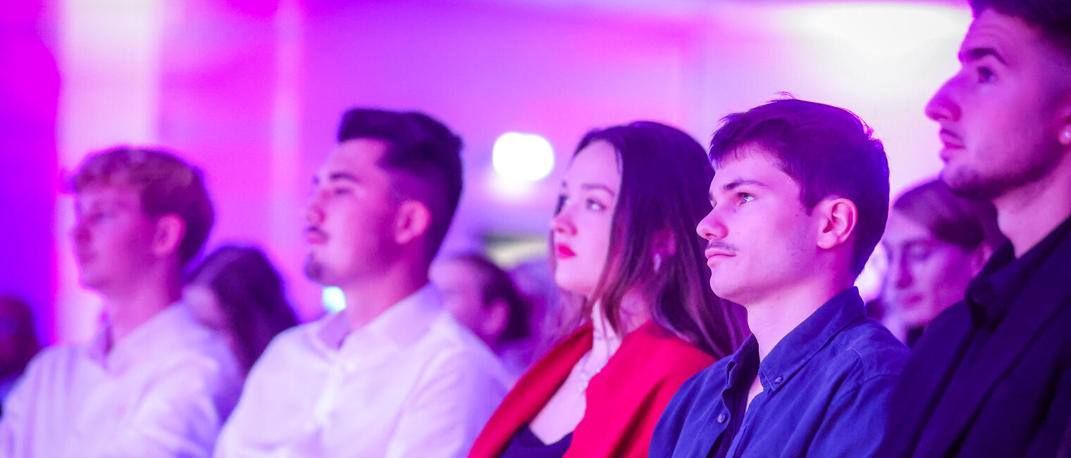 Die Landessiegerinnen und Landessieger sitzen im Publikum und hören zu.