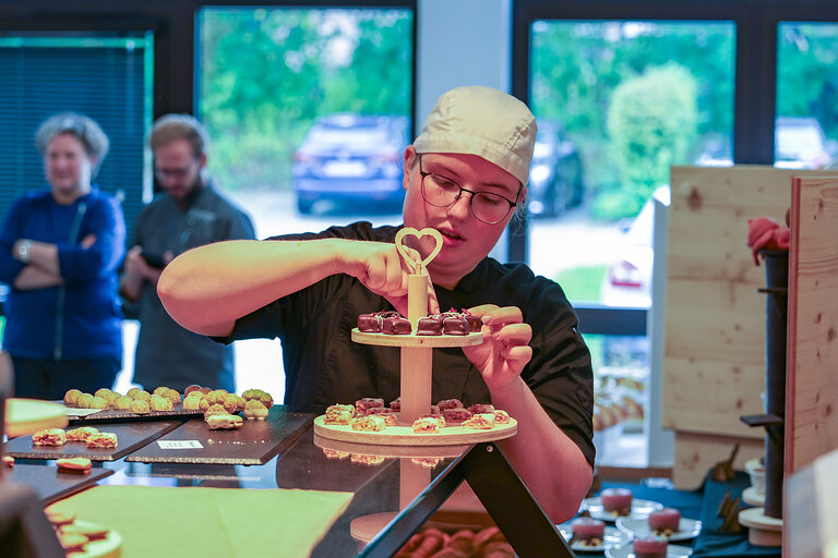 Eine junge Frau bereitet einen Präsentationsteller mit gebackenen Süßwaren vor.