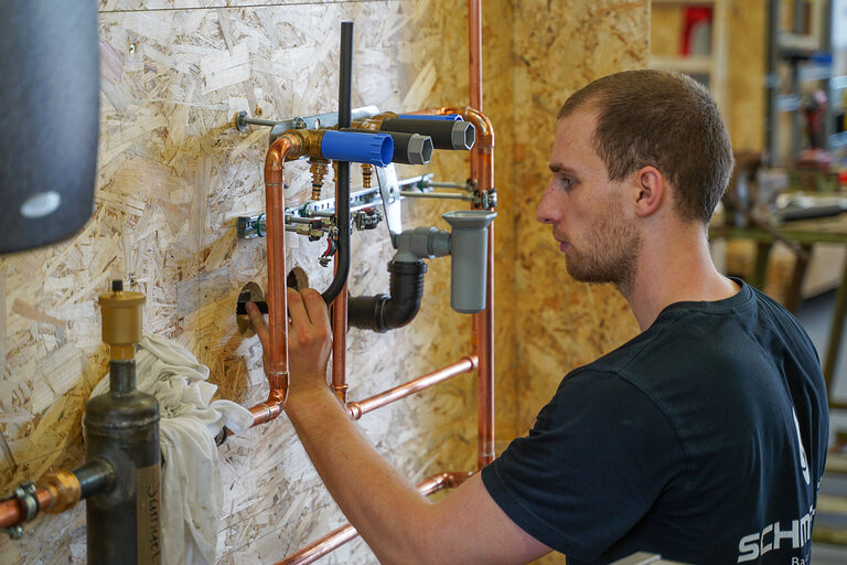 Ein junger Mann montiert ein Rohrsystem.