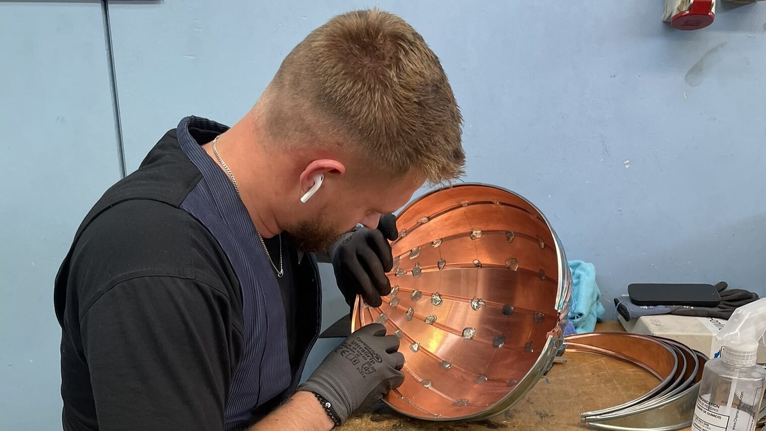 Ein junger Mann formt eine Kupferverschalung aus Metall.