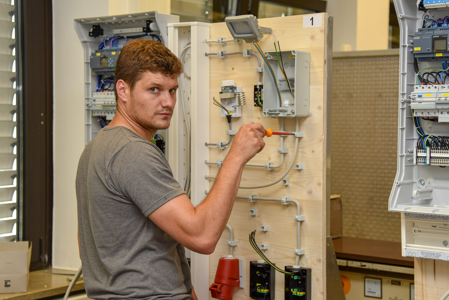 Ein junger Mann verkabelt einen Verteilerkasten.