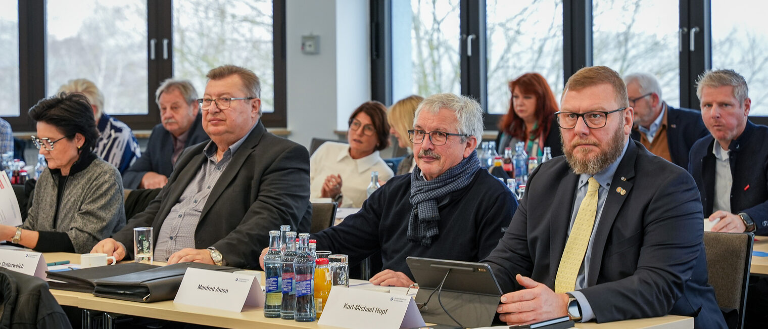 Mitglieder der Vollversammlung hören zu und machen sich Notizen auf Blocks und Tablets.