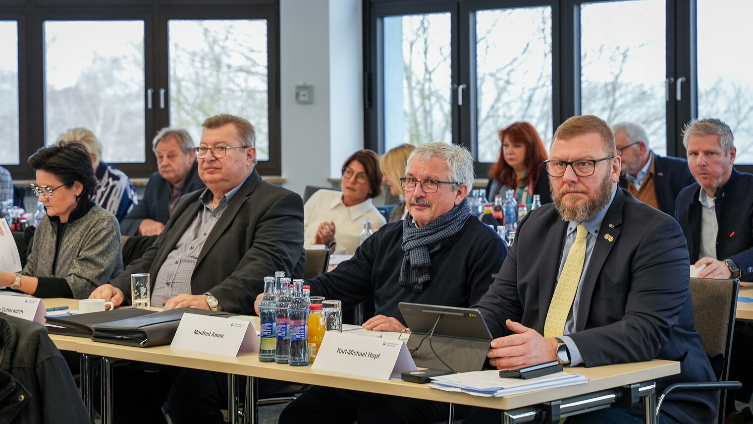 Mitglieder der Vollversammlung hören zu und machen sich Notizen auf Blocks und Tablets.