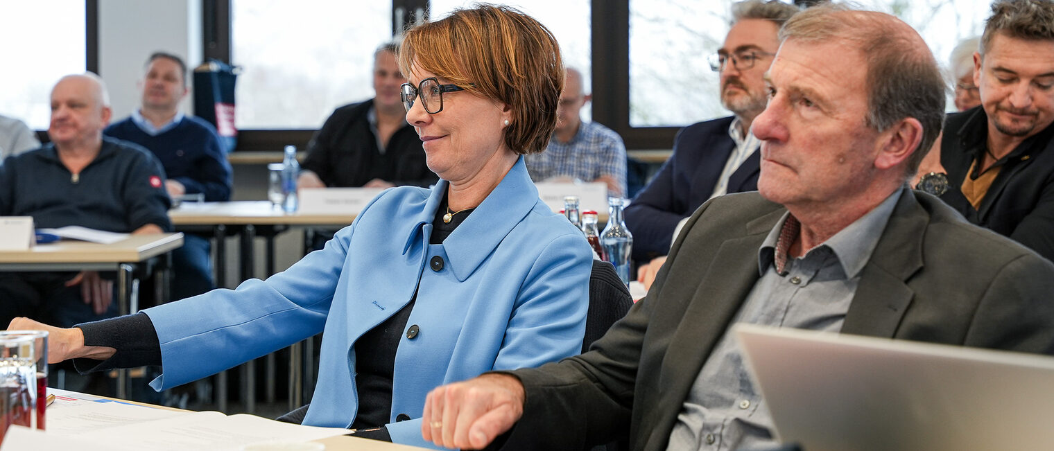 Zwei Mitglieder der Vollversammlung klopfen zustimmend auf den Tisch.