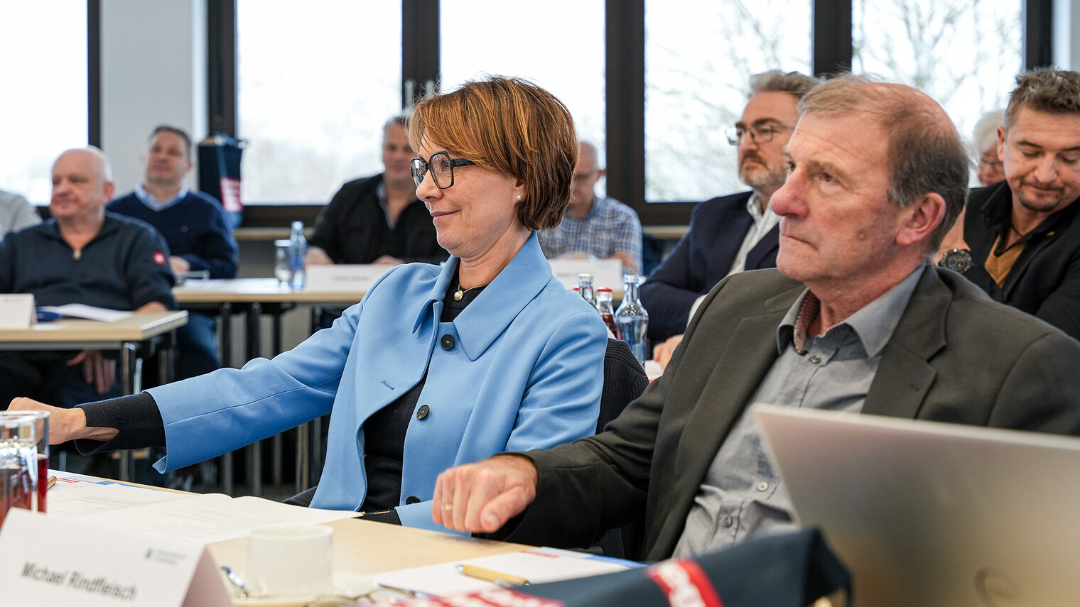 Zwei Mitglieder der Vollversammlung klopfen zustimmend auf den Tisch.