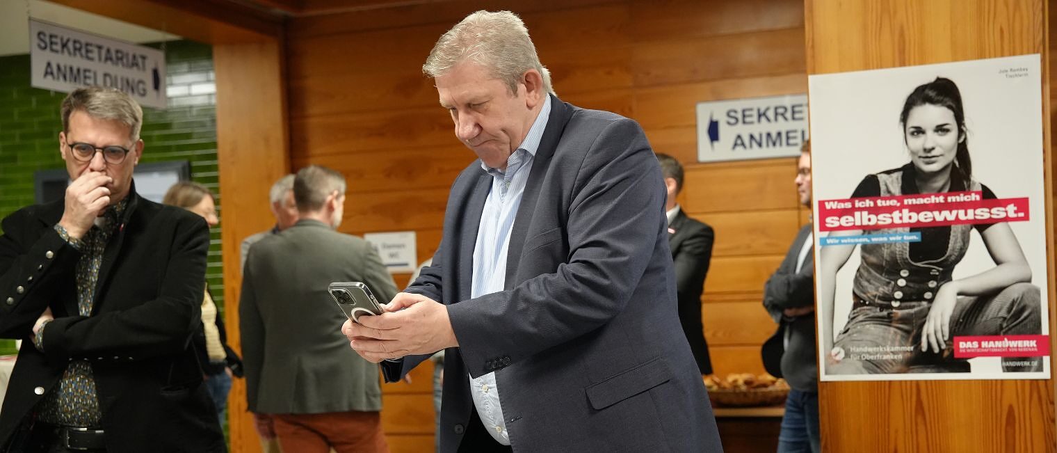 MdB Andreas Schwarz macht mit seinem Handy ein Foto vom Modell des Neubaus