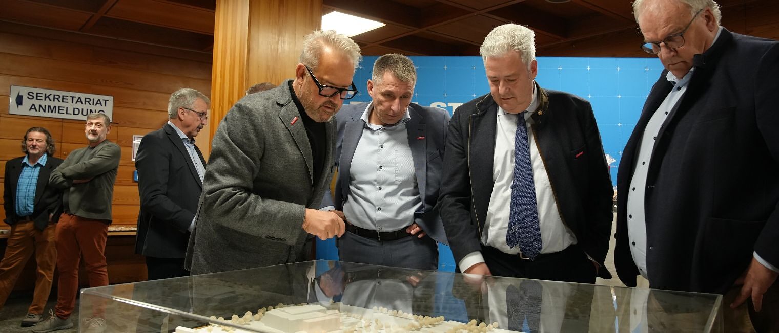 Verschiedene Personen zeigen auf das Modell des neuen Bildungszentrums Bamberg und diskutieren darüber