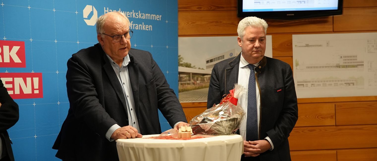 Der Hauptgeschäftsführer der Handwerkskammer steht neben dem Präsidenten der HWK und hält eine Ansprache
