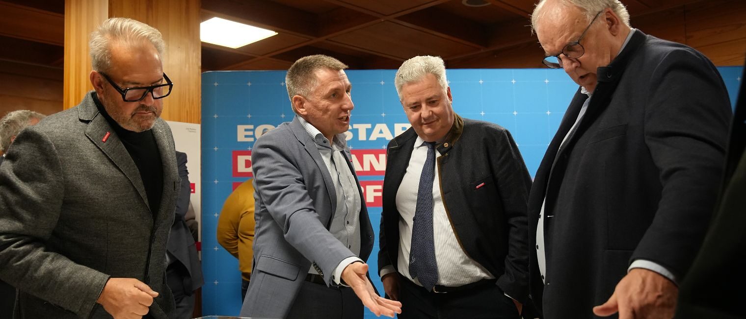 Verschiedene Personen zeigen auf das Modell des neuen Bildungszentrums Bamberg und diskutieren darüber