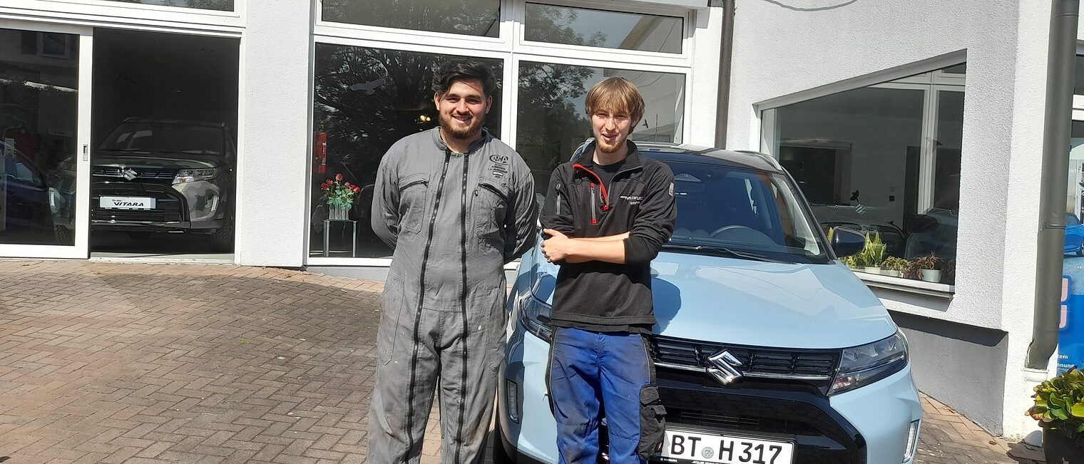 Ein französischer Azubi posiert mit einem Ausbilder vor dem Autohaus Hauswurz.