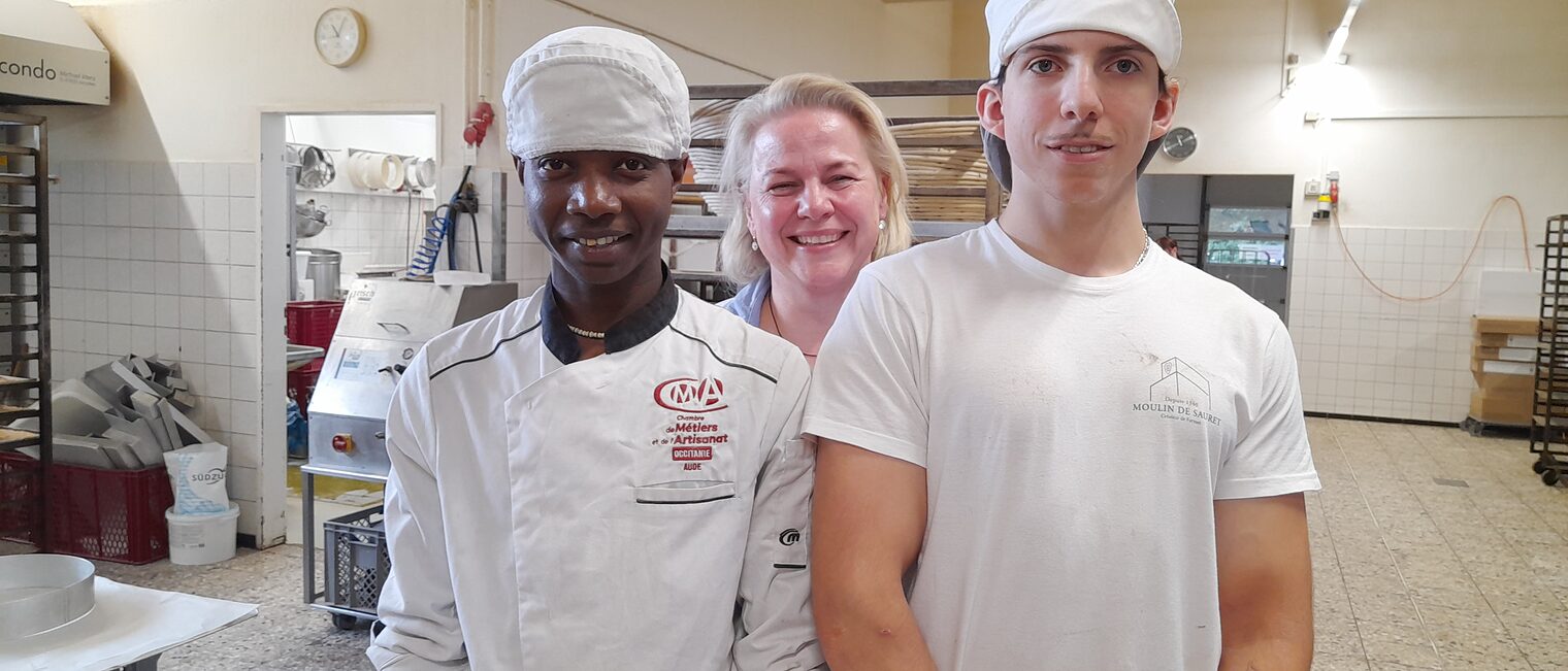 Zwei französische Azubis posieren mit einer Ausbilderin in einer Bäckerei in Gesees.