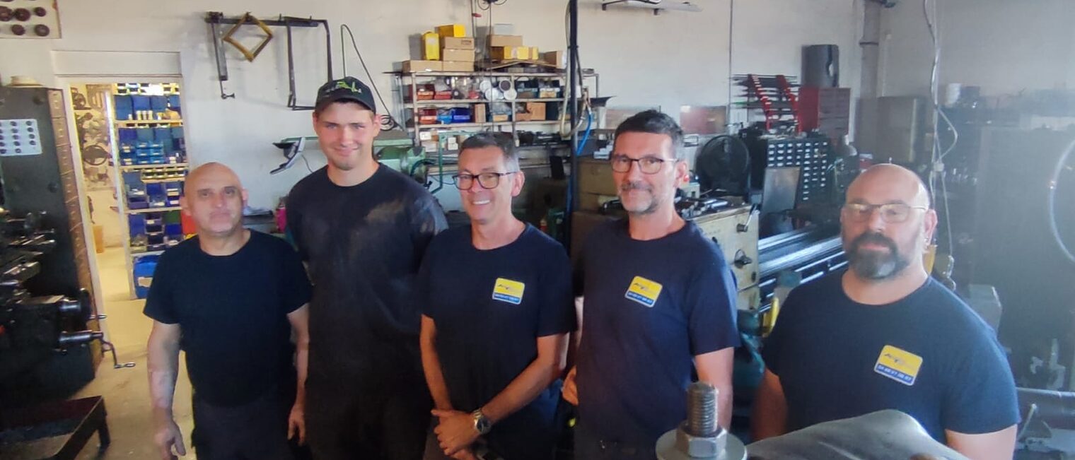 Deutsche Azubis stehen mit Ausbildungsleitern in einer Metallbauwerkstatt in Lezignan.