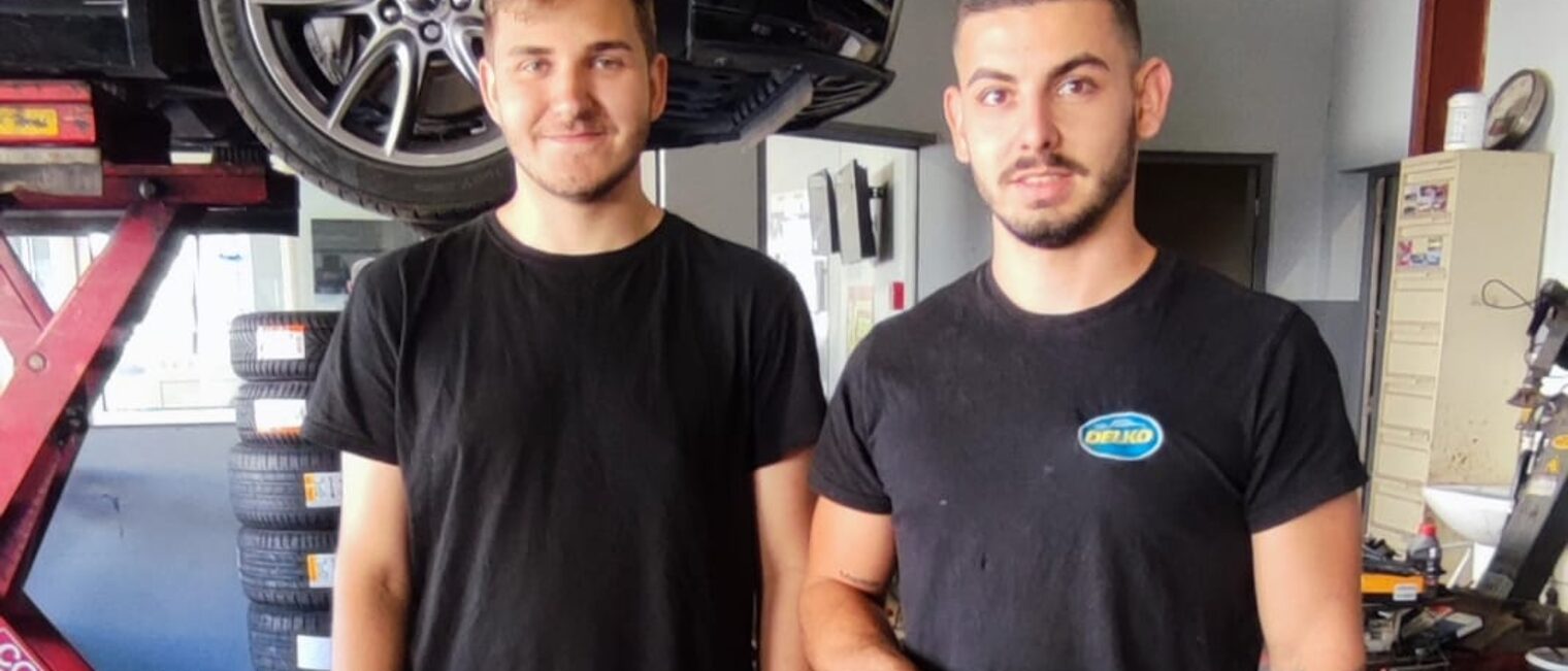 Ein deutscher Azubi steht neben einem Ausbilder in einer Autowerkstatt in Lezignan.