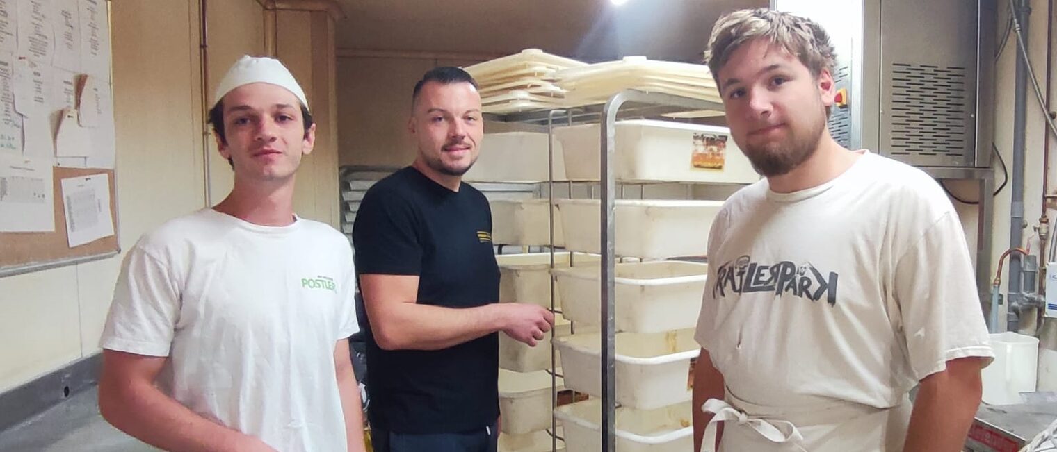 Zwei deutsche Auszubildende stehen mit einem Ausbilder in Lagerbereich einer Bäckerei in Lezignan.