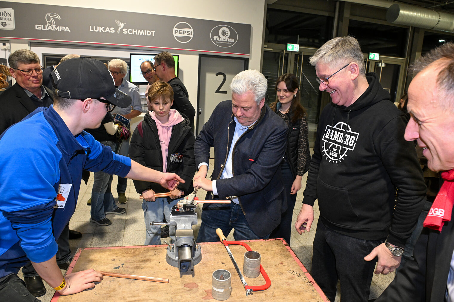 HWK-Präsident Matthias Graßmann biegt unter Aufsicht ein Metallrohr zurecht. 