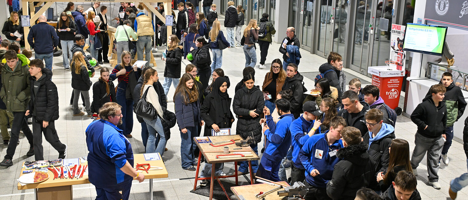 Luftaufnahme der Stände der Betriebe mit den Schülerinnen und Schülern im Foyer der Brose-Arena.