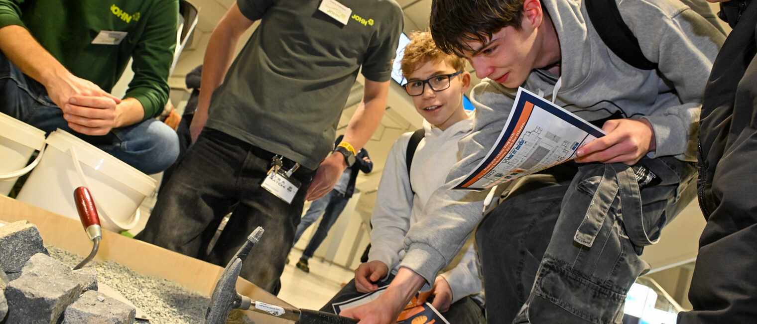 Ein Schüler pflastert einen Weg während andere Schüler ihm zusehen.